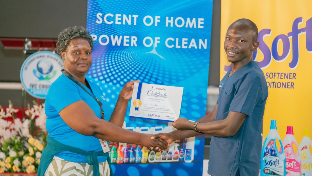HACO Industries Home care Category Manager, Joan Chege (L) presenting a certificate to Brian Juma a participant(R) after a successful completion of the training.