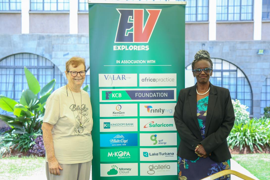 Two women stand beside an EV Explorers banner displaying KCB Foundation and other partner logos.