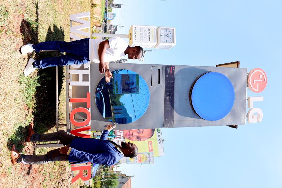 Two men stand beside a large LG WashTower promotional installation at an outdoor showcase in Nairobi.